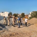 आगरा में आवास विकास परिषद की टीम जेसीबी से अवैध कब्जा हटाते हुए, मौके पर मौजूद अधिकारी और भीड़।