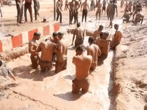 साथी पुलिसकर्मी को कीचड़ में ले जाते जवान