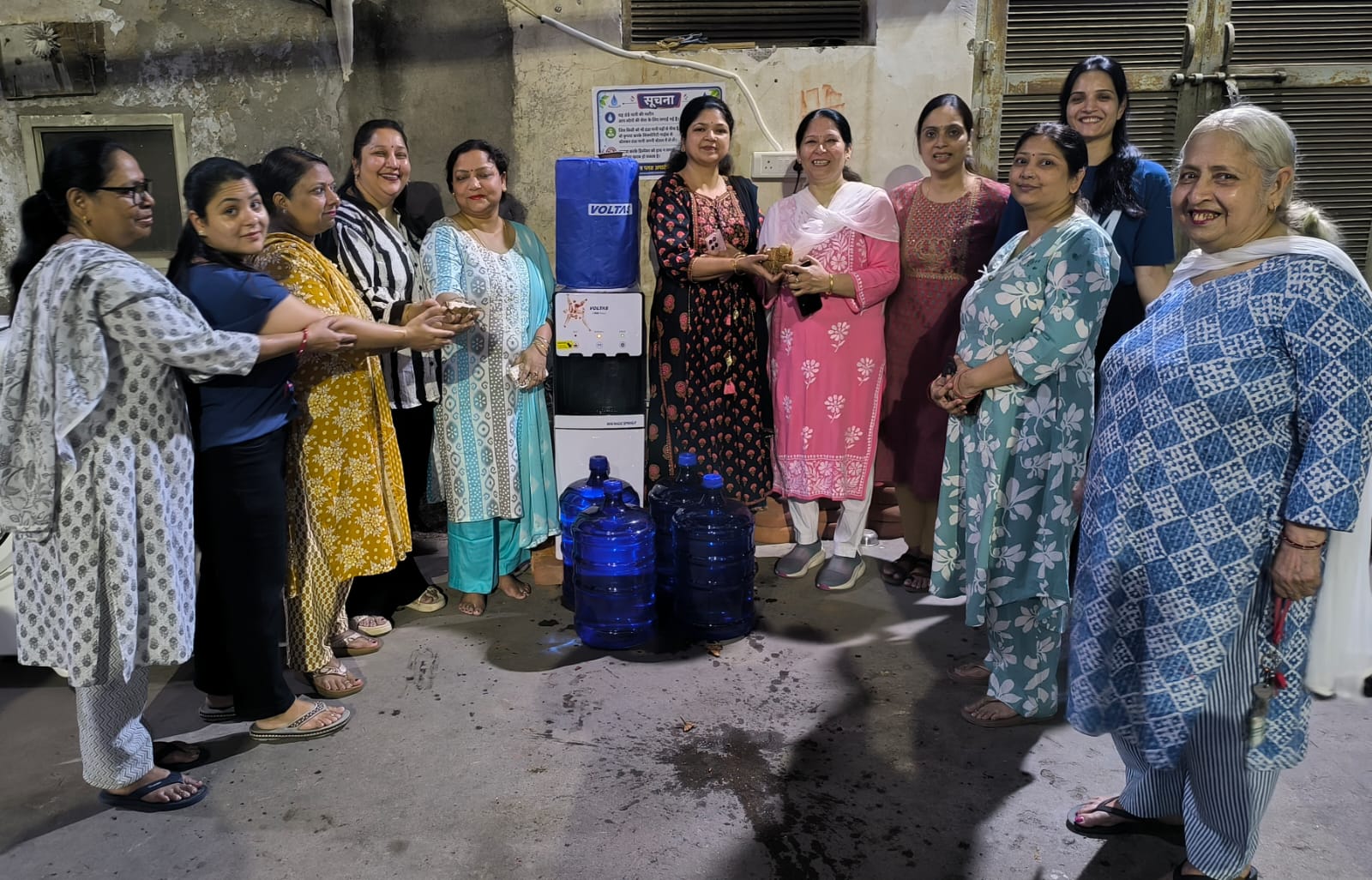 पारस पर्ल्स अपार्टमेंट में शीतल जल मशीन का पूजा-अर्चना कर शुभारंभ करती हुईं महिलाएं