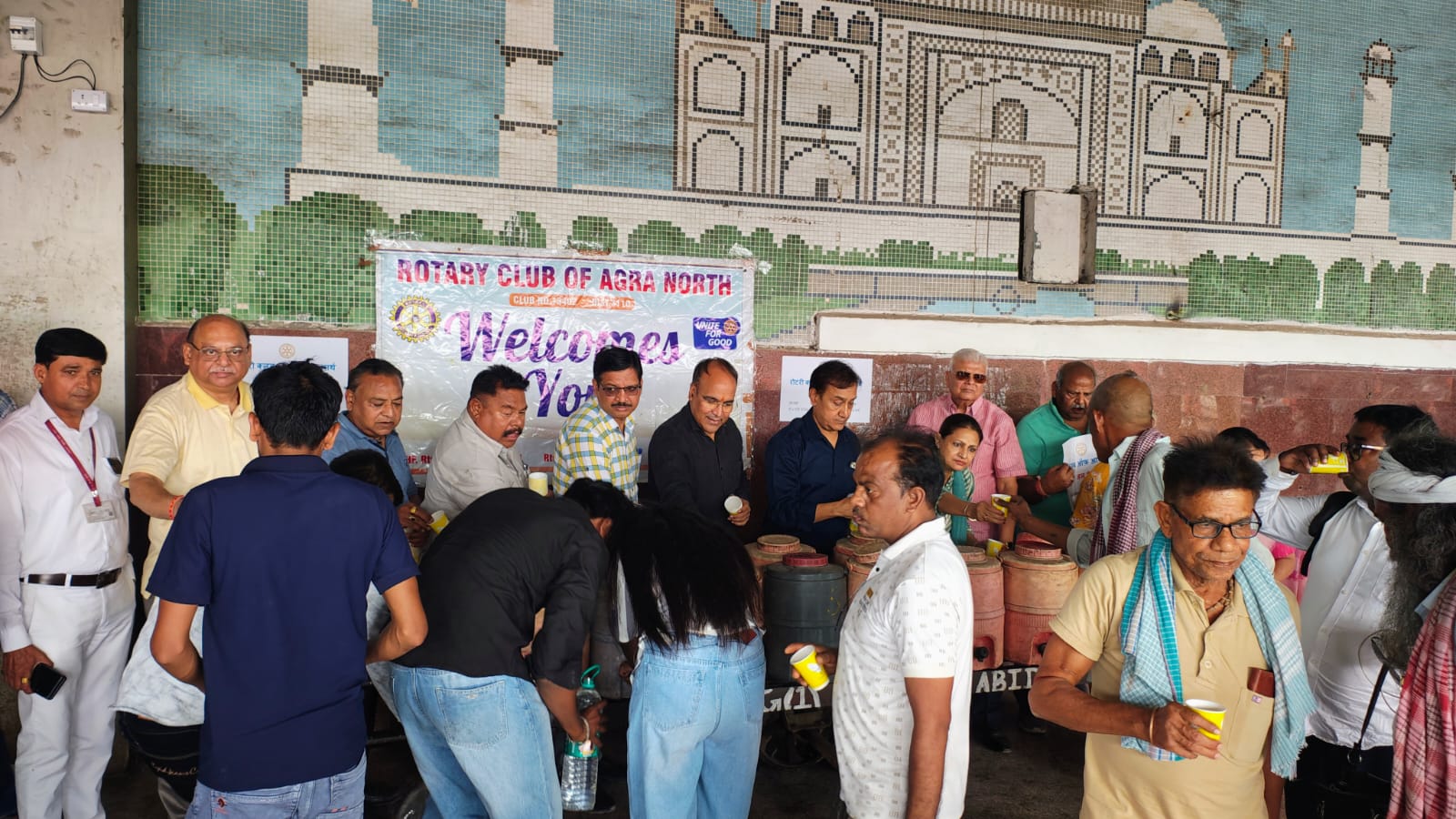 ट्रेन की खिड़कियों पर जाकर यात्रियों को पानी पिलाते हुए रोटरी क्लब आगरा के सदस्य