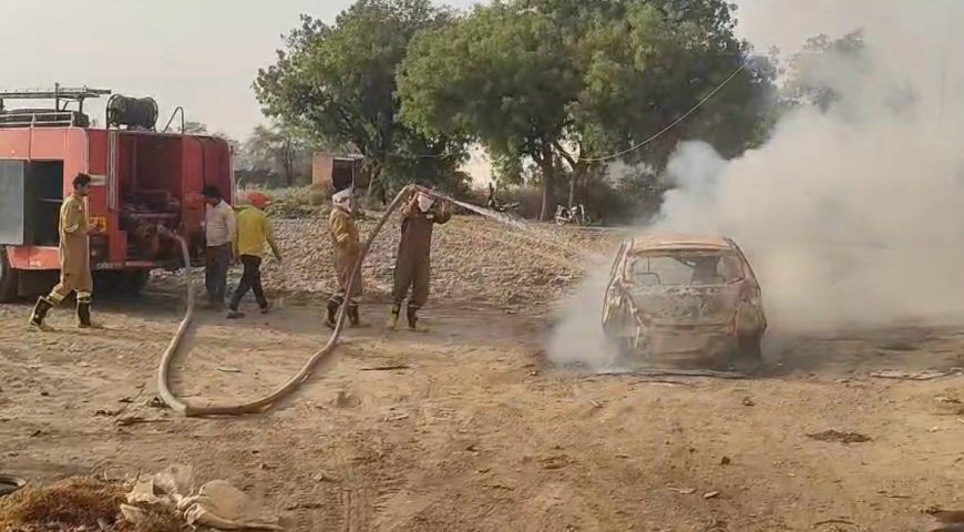 Firefighters dousing fire in a Tata Tiago car caught in flames on the roadside in Saiyan Agra