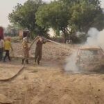 Firefighters dousing fire in a Tata Tiago car caught in flames on the roadside in Saiyan Agra