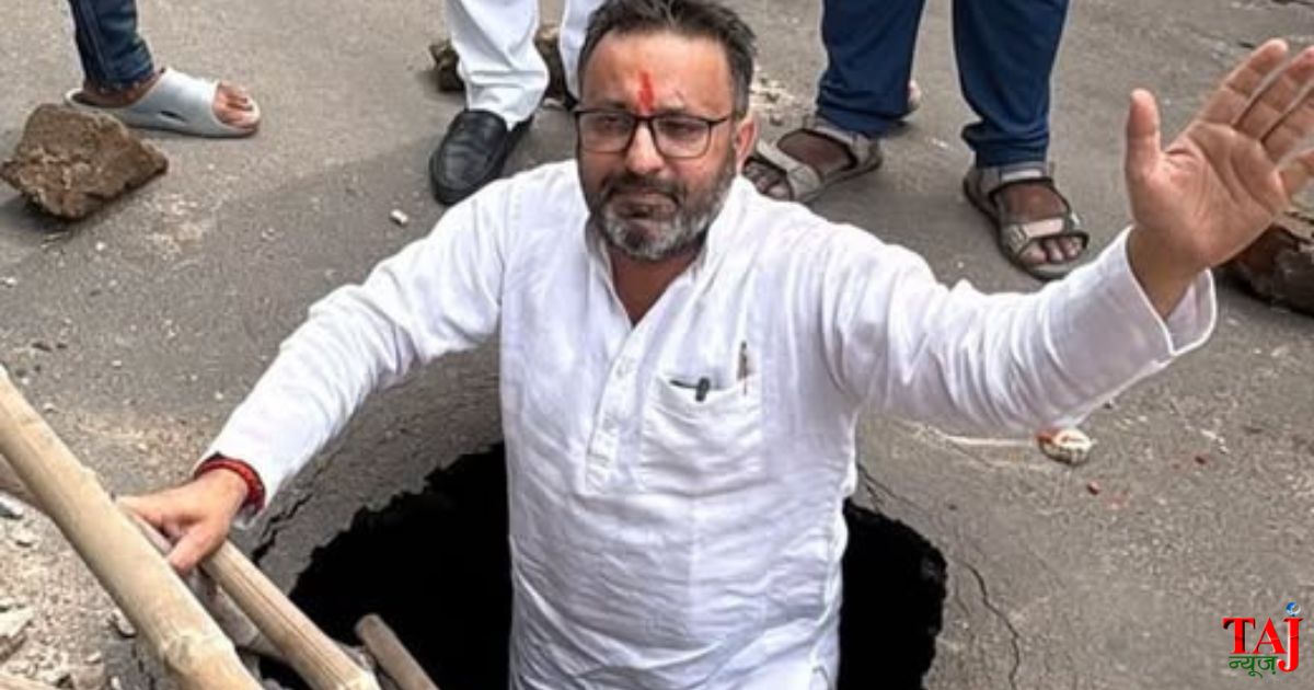आगरा के पॉश कॉलोनी कमला नगर में बदहाल सड़क पर बने गहरे गड्ढे में लोहे की सीढ़ी लगाकर अनूठा विरोध प्रदर्शन करते सपा नेता नितिन कोहली