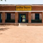 आगरा के एक जर्जर प्राथमिक विद्यालय के बरामदे में बैठकर पढ़ाई करते हुए मासूम बच्चों